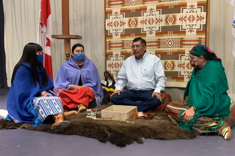 Joanne Polec, Emily Fox, and Annette Bruised Head around Tom Little Bear before he paints their faces.